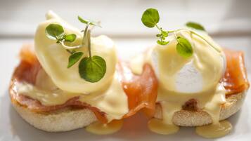 A close-up of a dish with eggs, ham, and a creamy sauce, garnished with a small green leaf.