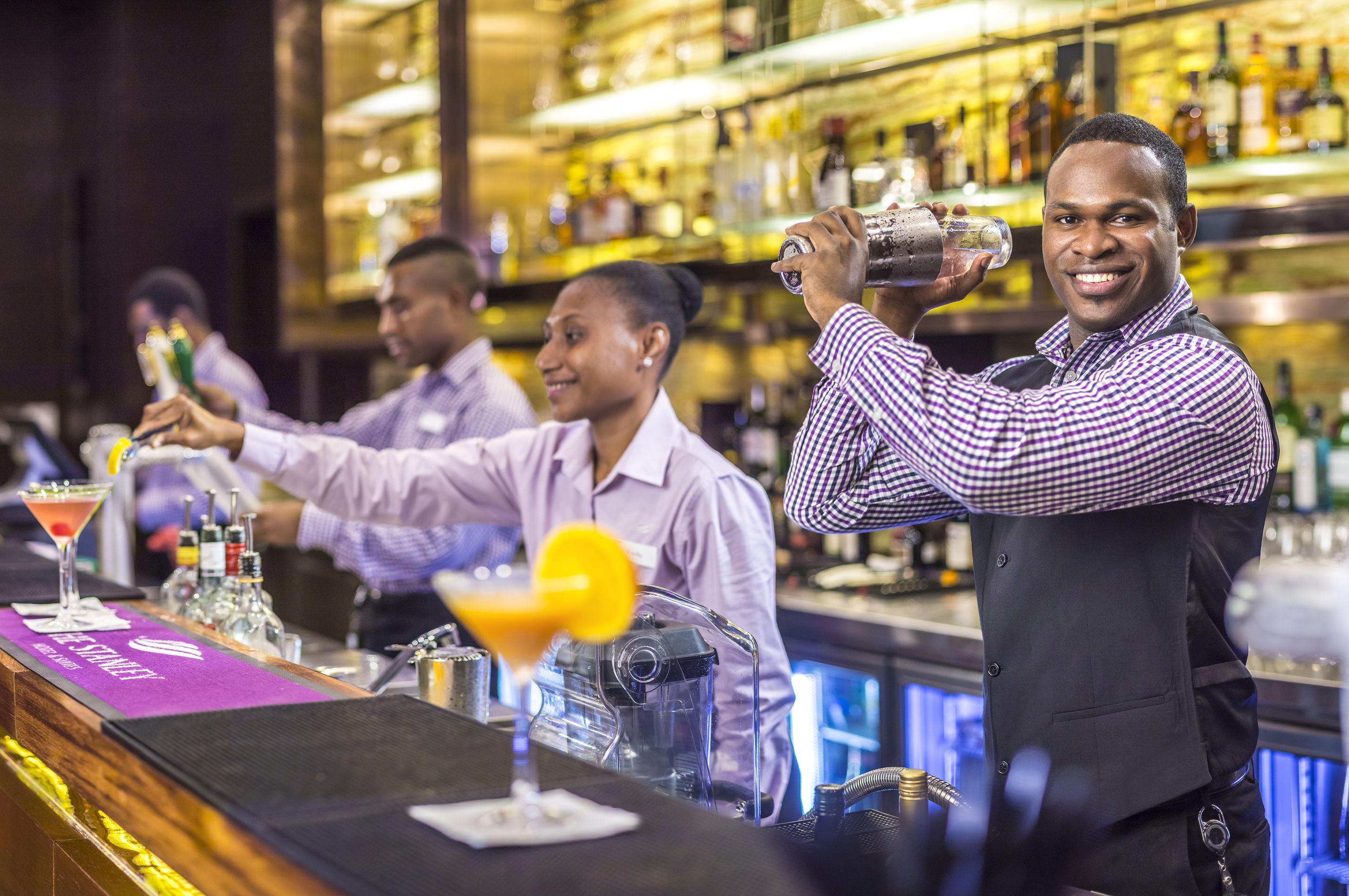 A bar setting with bartenders preparing drinks.