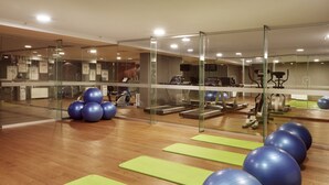 Une salle de sport équipée de matériel d’exercice, de tapis verts et de ballons bleus pour faire de l’exercice.