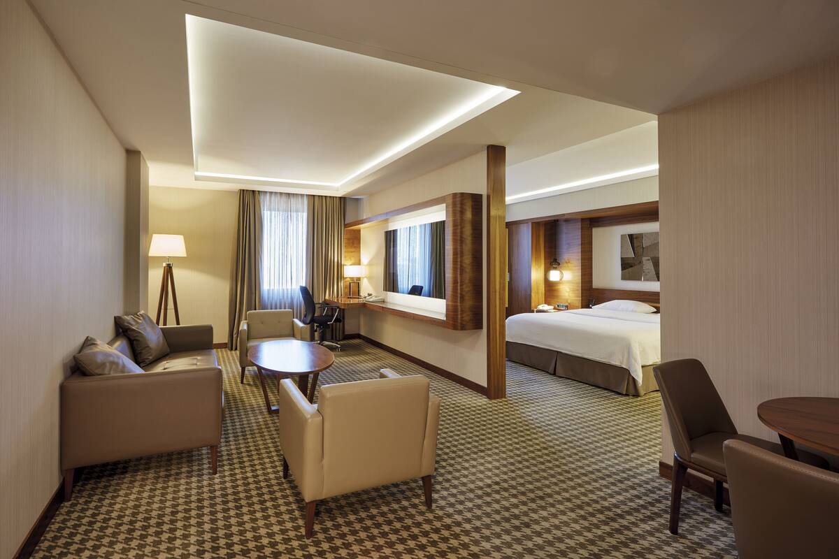 Una habitación de hotel con cama, sofá, escritorio y silla.