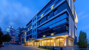Un hôtel moderne, doté de plusieurs étages, de grandes fenêtres et d’une entrée bien éclairée.