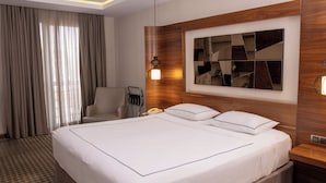 Une chambre d’hôtel avec un grand lit, une tête de lit en bois, un miroir et un bureau avec une lampe.