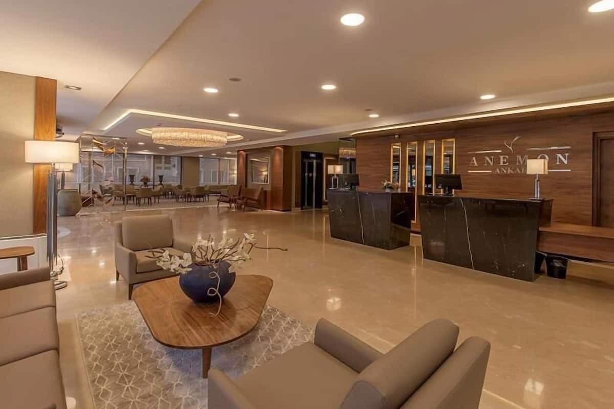 Un vestíbulo de hotel moderno con mostrador de recepción, zona de estar y una araña.