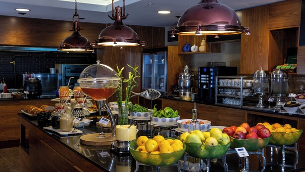 Un buffet proposant une variété de plats et de boissons, notamment des saladiers de fruits et un coin café.
