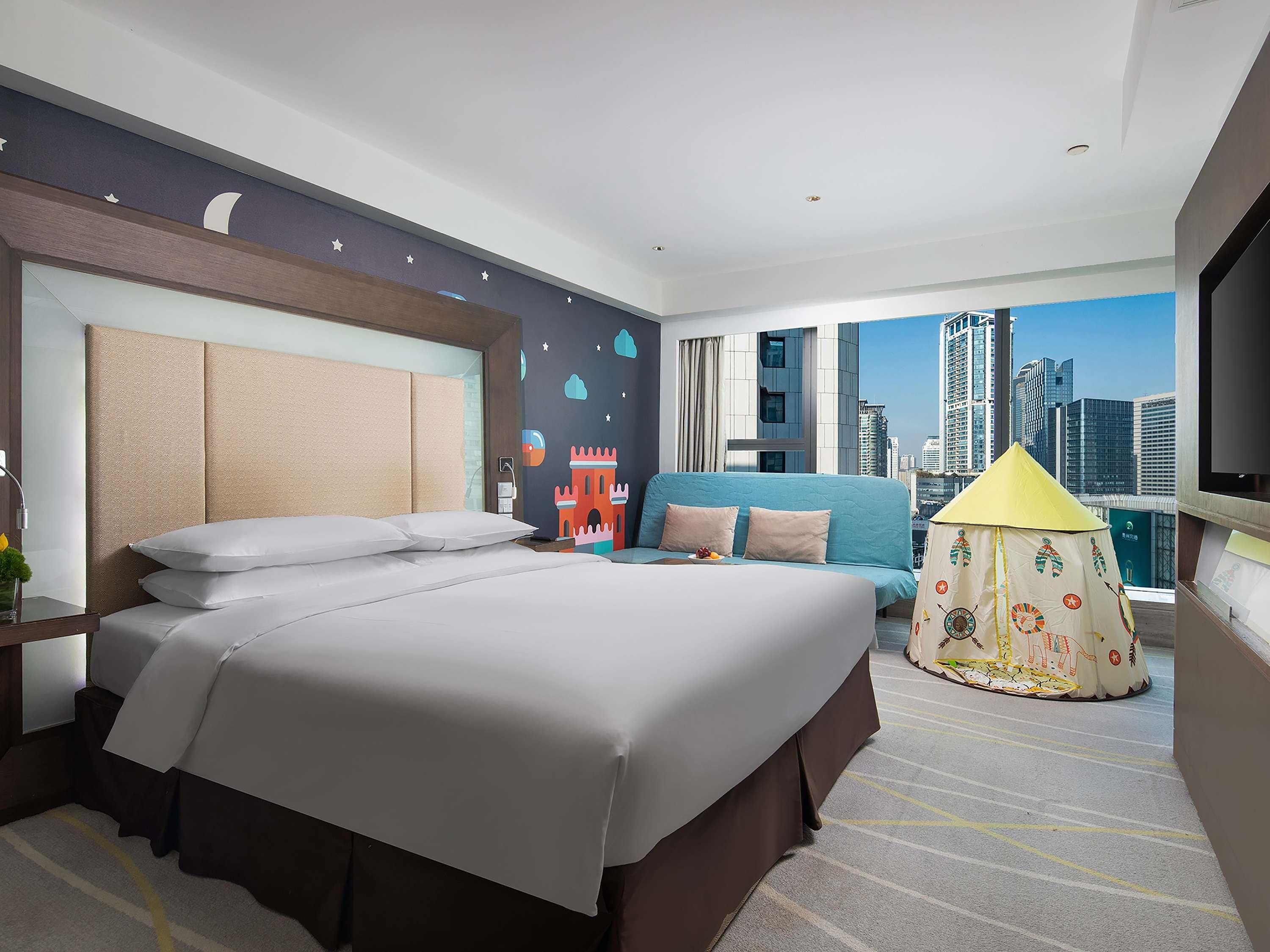 Ein Hotelzimmer mit einem großen Bett, einer Couch, einem Zelt zur Dekoration und Blick auf die Stadt.