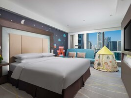 Ein Hotelzimmer mit einem großen Bett, einer Couch, einem Zelt zur Dekoration und Blick auf die Stadt.