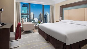 A hotel room with a large bed, a desk, a chair, and a view of a city skyline. - Novotel Nanjing Central Suning (Nanjing)