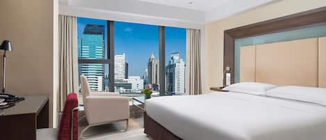 Una habitación de hotel con una cama grande, un escritorio, una silla y vistas a un horizonte urbano.