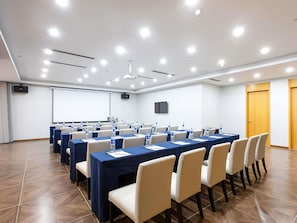 A conference room with multiple tables, chairs, a projector screen, and a whiteboard. - Novotel Nanjing Central Suning (Nanjing)