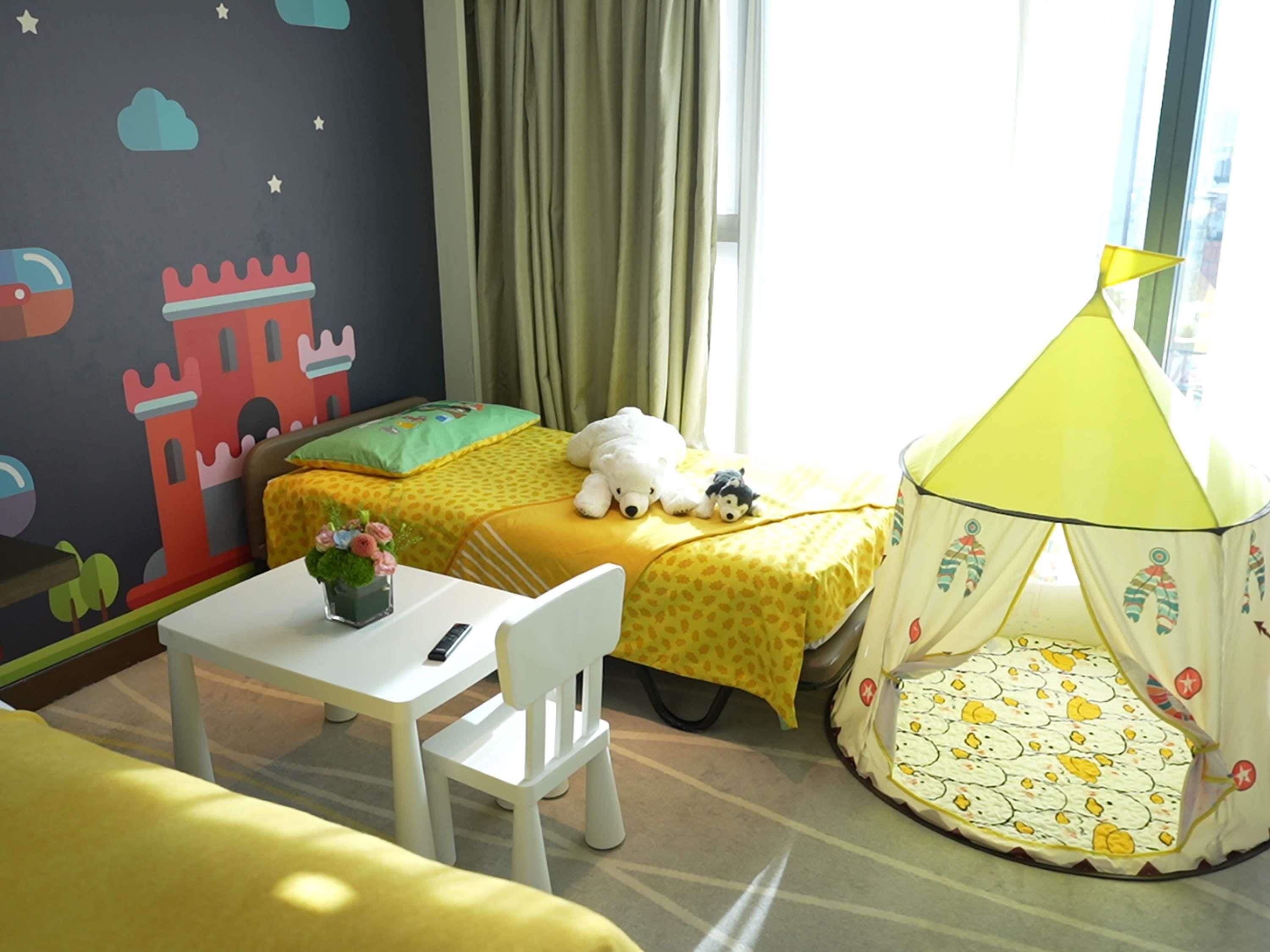 A child's bedroom with a bed, a small table, a chair, a tent, and a wall with a castle mural.