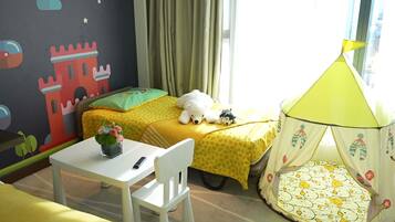 A child's bedroom with a bed, a small table, a chair, a tent, and a wall with a castle mural.