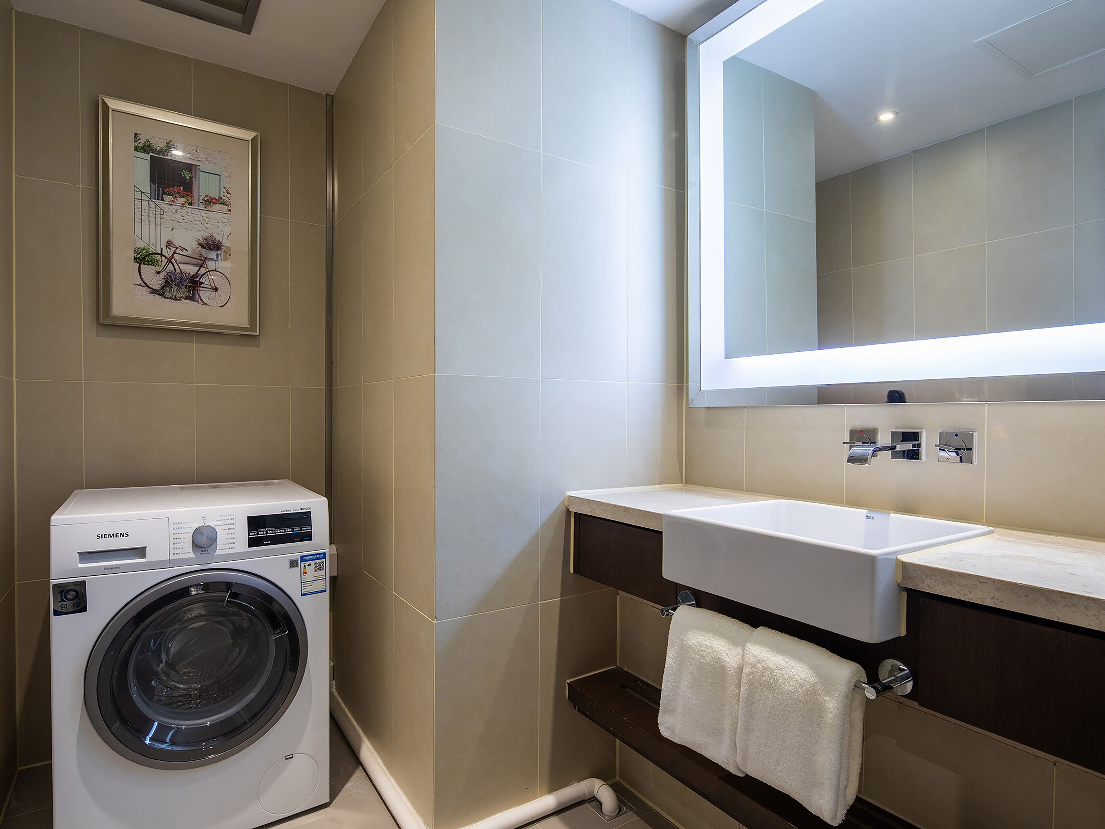 Un baño moderno con lavadora, lavamanos y espejo.