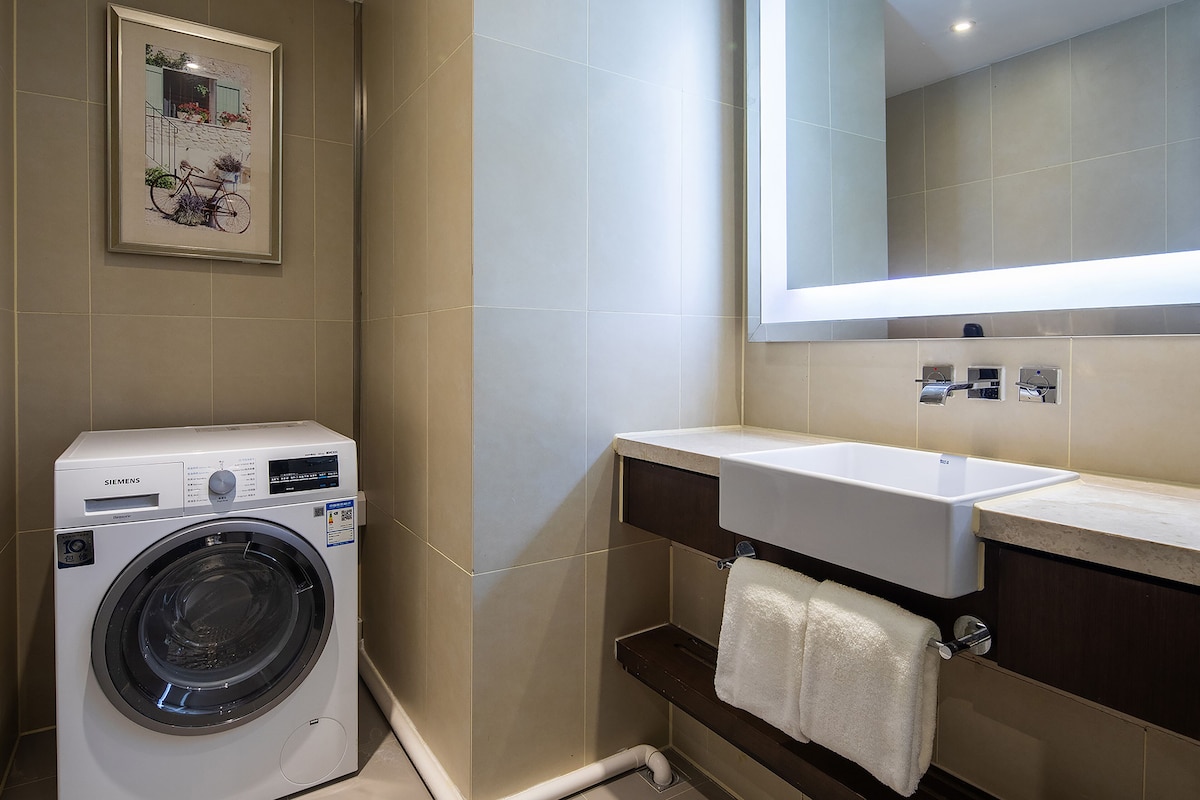 Un baño moderno con lavadora, lavamanos y espejo.