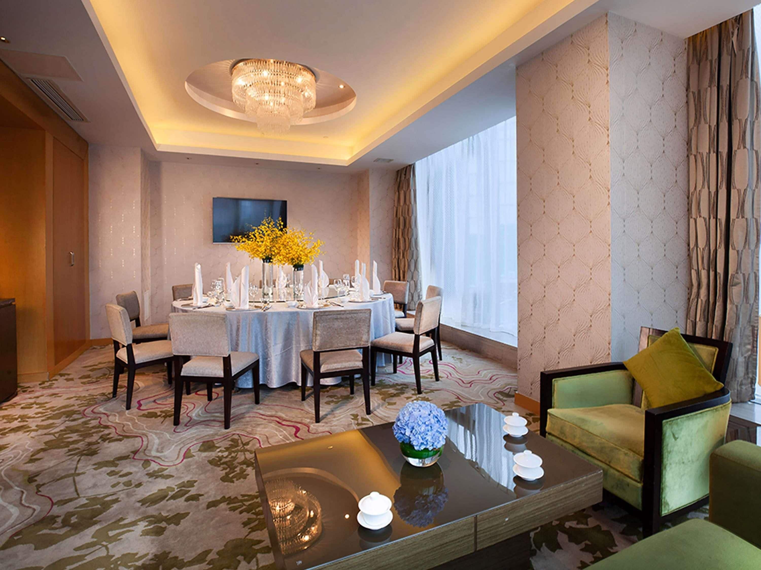 A hotel room with a dining area, a sofa, and a chandelier.