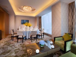 A hotel room with a dining area, a sofa, and a chandelier.