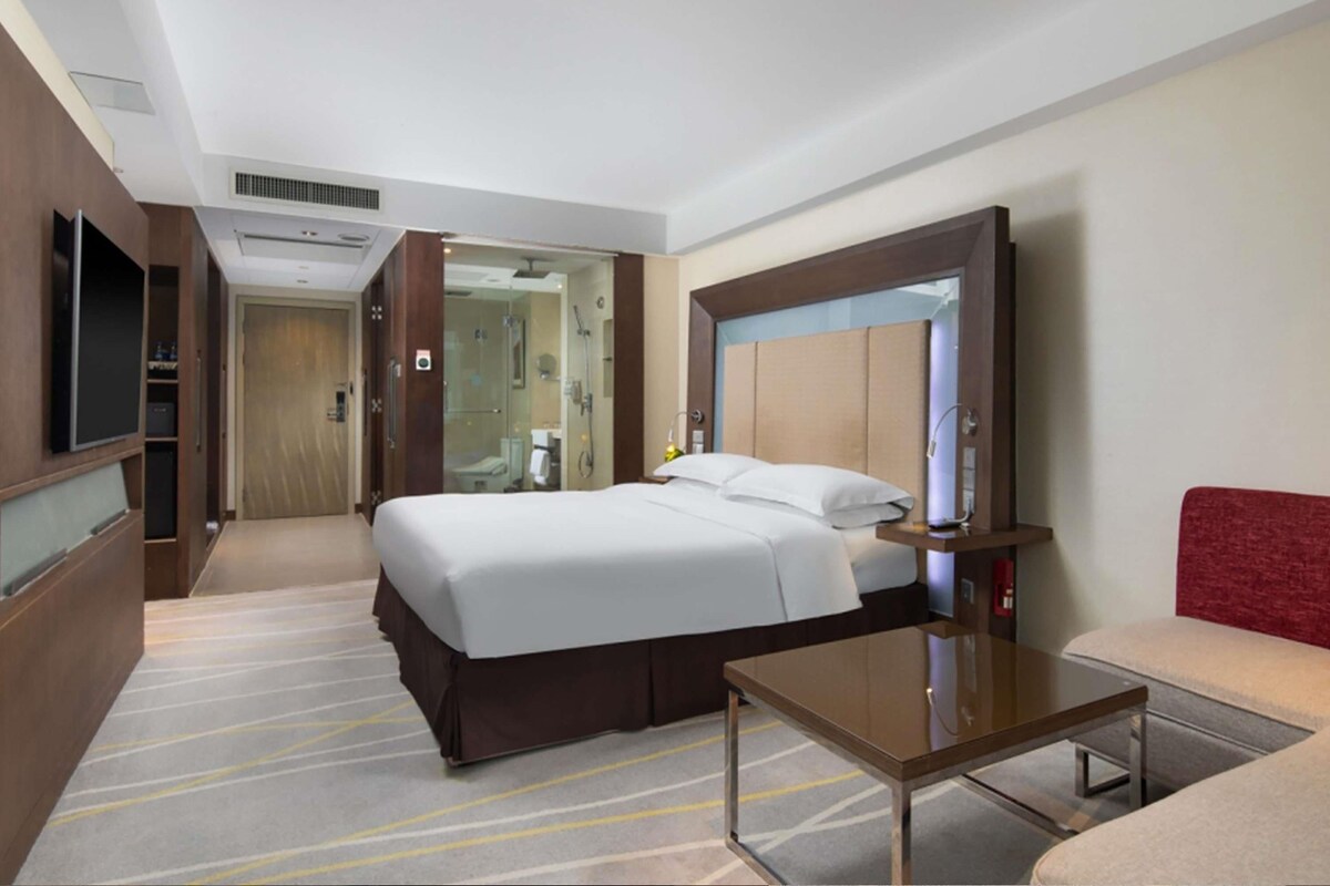 Une chambre d’hôtel équipée d’un lit, d’une télévision, d’un bureau et d’un miroir.