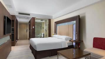 Una habitación de hotel con cama, televisión, escritorio y espejo.