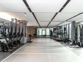 Un gimnasio moderno con máquinas de cardio, equipo de levantamiento de pesas y espejos en las paredes.
