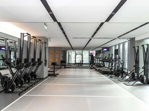 Un gimnasio moderno con máquinas de cardio, equipo de levantamiento de pesas y espejos en las paredes.