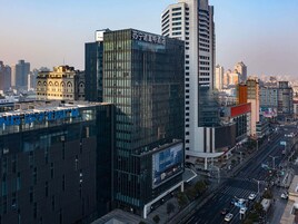 Un hotel moderno con fachada de vidrio y señalización en un paisaje urbano.