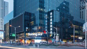 A modern building with reflective glass windows and a prominent 'Suning' sign at the ground level. - Novotel Nanjing Central Suning (Nanjing)