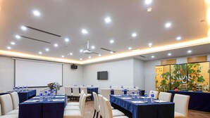A conference room with tables, chairs, water bottles, a projector screen, and a decorative screen with birds. - Novotel Nanjing Central Suning (Nanjing)