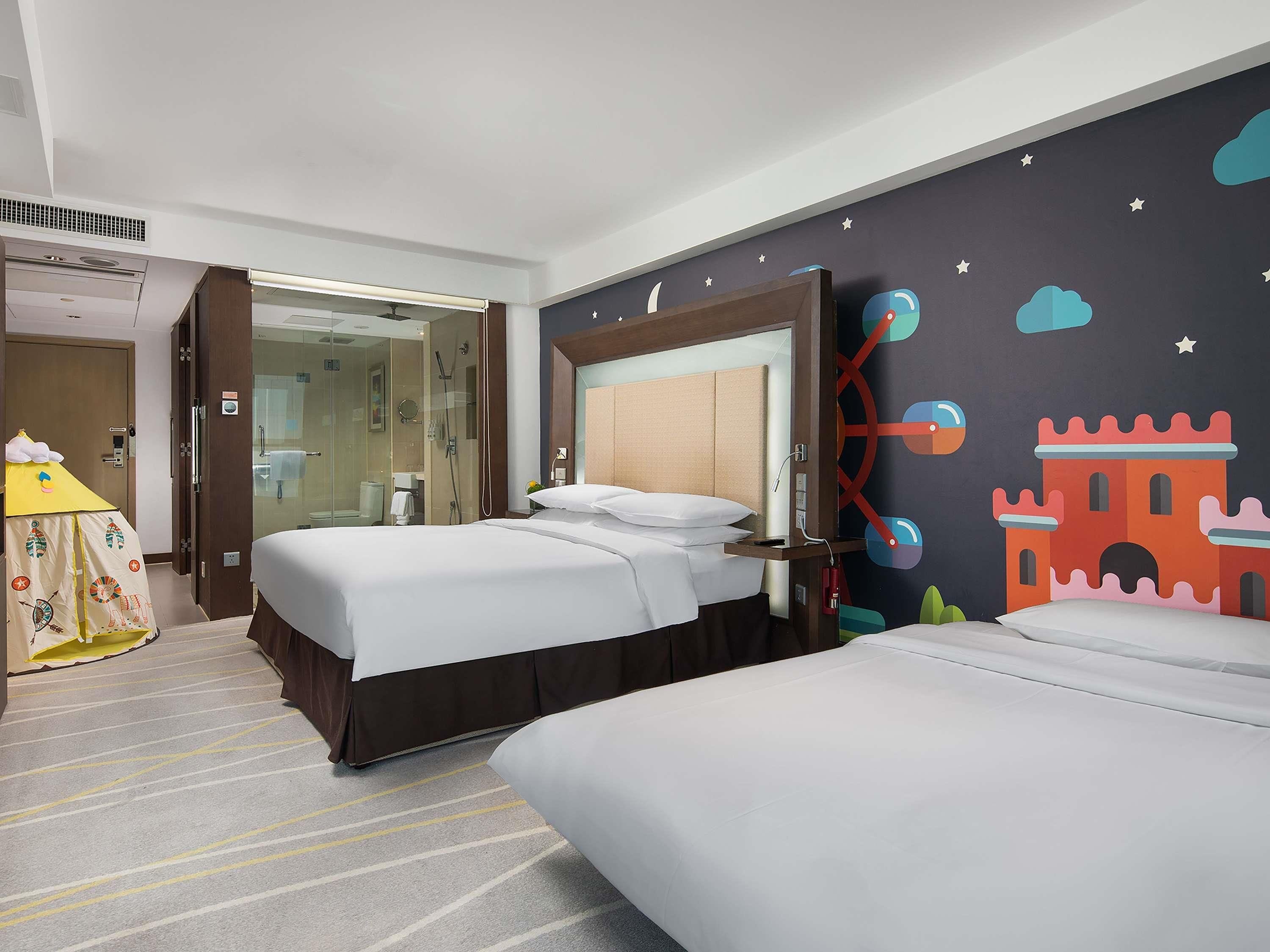 Habitación de hotel con dos camas, zona de ducha y un mural con un castillo en la pared.