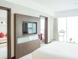 Habitación de hotel con cama, televisor montado, escritorio y vista al exterior.