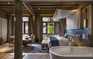 A modern bathroom with a freestanding bathtub, a large mirror, and a window with a view of greenery. - LUX Tea Horse Road Lijiang (Lijiang)