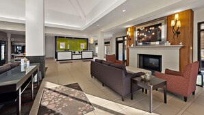A modern hotel lobby with a sofa, armchairs, a fireplace, and a television. - Hilton Garden Inn Findlay (Findlay)