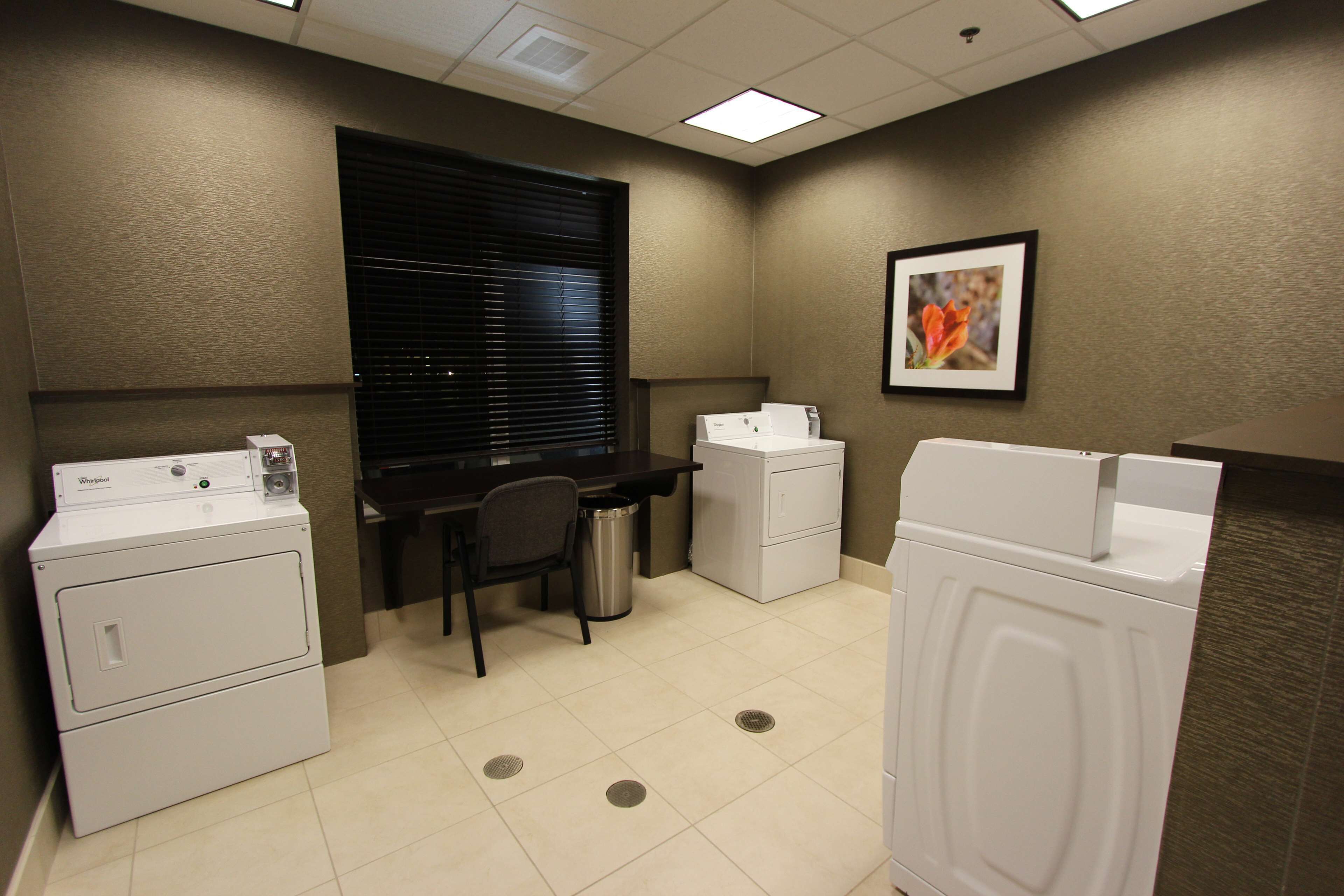 A laundry room with two front-loading washers, a desk, and a trash can.