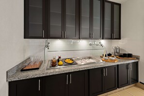A modern kitchen with dark cabinets, a granite countertop, a stainless steel sink, and various kitchen items.