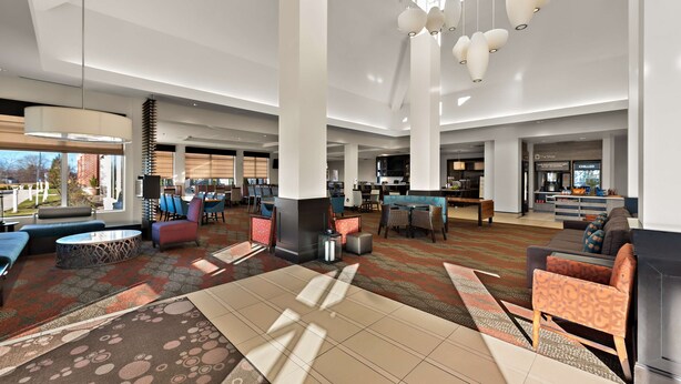 A spacious lobby with high ceilings, modern lighting fixtures, and a variety of seating options including sofas and chairs. - Hilton Garden Inn Findlay (Findlay)