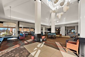 A spacious lobby with high ceilings, modern lighting fixtures, and a variety of seating options including sofas and chairs.
