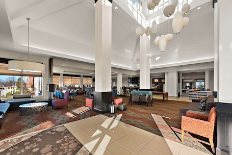 A spacious lobby with high ceilings, modern lighting fixtures, and a variety of seating options including sofas and chairs.