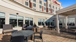 An outdoor patio area with tables and chairs, a fire pit, and a building with a sign that reads "Holiday Inn Express." - Hilton Garden Inn Findlay (Findlay)