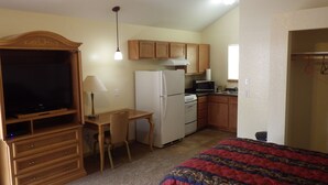 A compact room with a kitchenette, a dining area, and a bed. - Brush Country Lodge (Pleasanton)