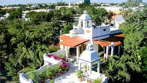 A white building with a red roof, surrounded by lush greenery and a clear sky. - Eco-Hotel El Rey del Caribe (Cancun)