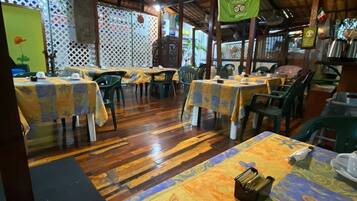 A restaurant with wooden floors, tables with colorful tablecloths, and a high ceiling with exposed beams.