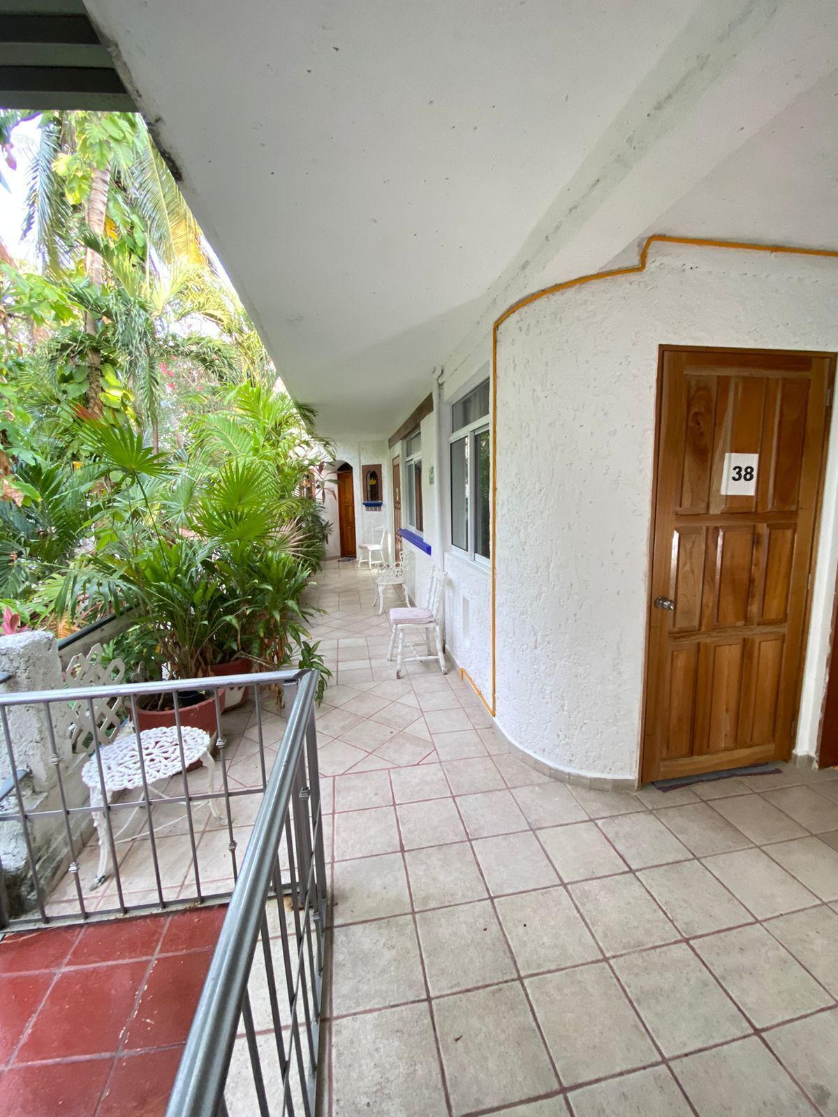 A corridor with a tiled floor, white walls, and a wooden door marked with the number 38.