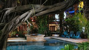 A pool area with a stone fountain, surrounded by lush greenery and blue Adirondack chairs. - Eco-Hotel El Rey del Caribe (Cancun)