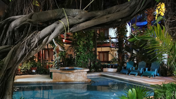A pool area with a stone fountain, surrounded by lush greenery and blue Adirondack chairs. - Eco-Hotel El Rey del Caribe (Cancun)