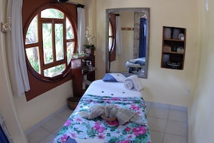 Una habitación con una cama, una ventana, un espejo y un estante con toallas.