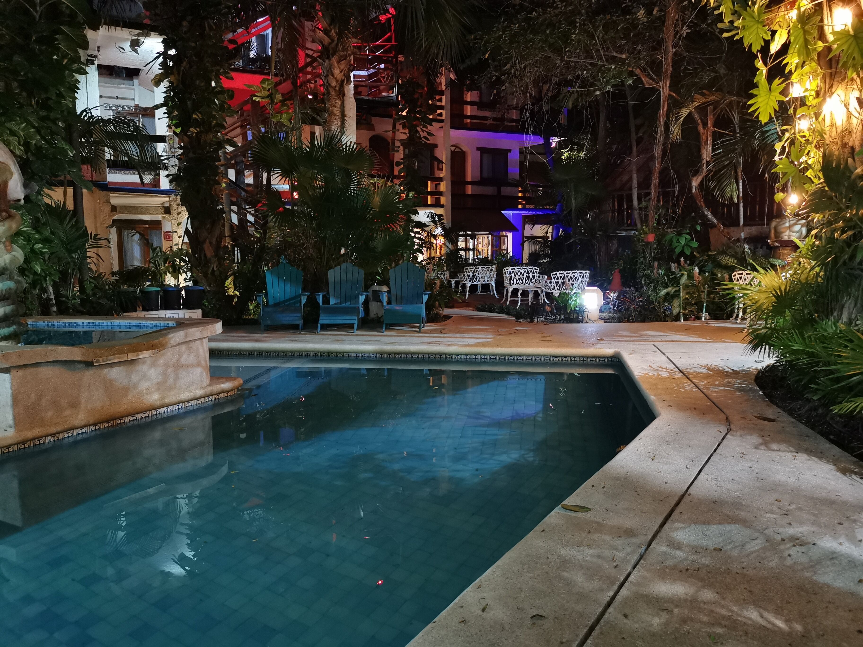 Ein Schwimmbadbereich bei Nacht mit Blick auf ein Gebäude im Hintergrund.