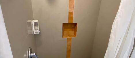 Un espacio de ducha con ducha de mano, toallero y cortina de baño.