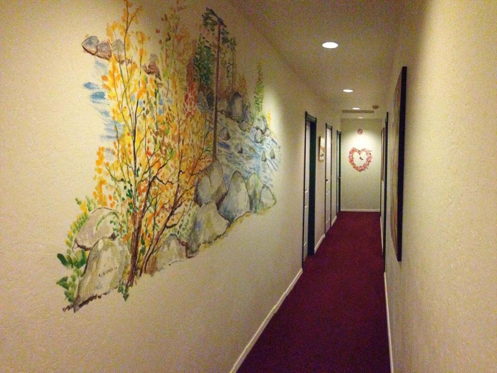 A hallway with a mural of trees and a heart-shaped decoration on the wall.