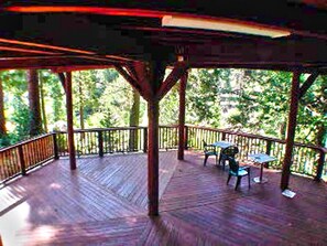 An outdoor wooden deck with a railing, surrounded by trees.
