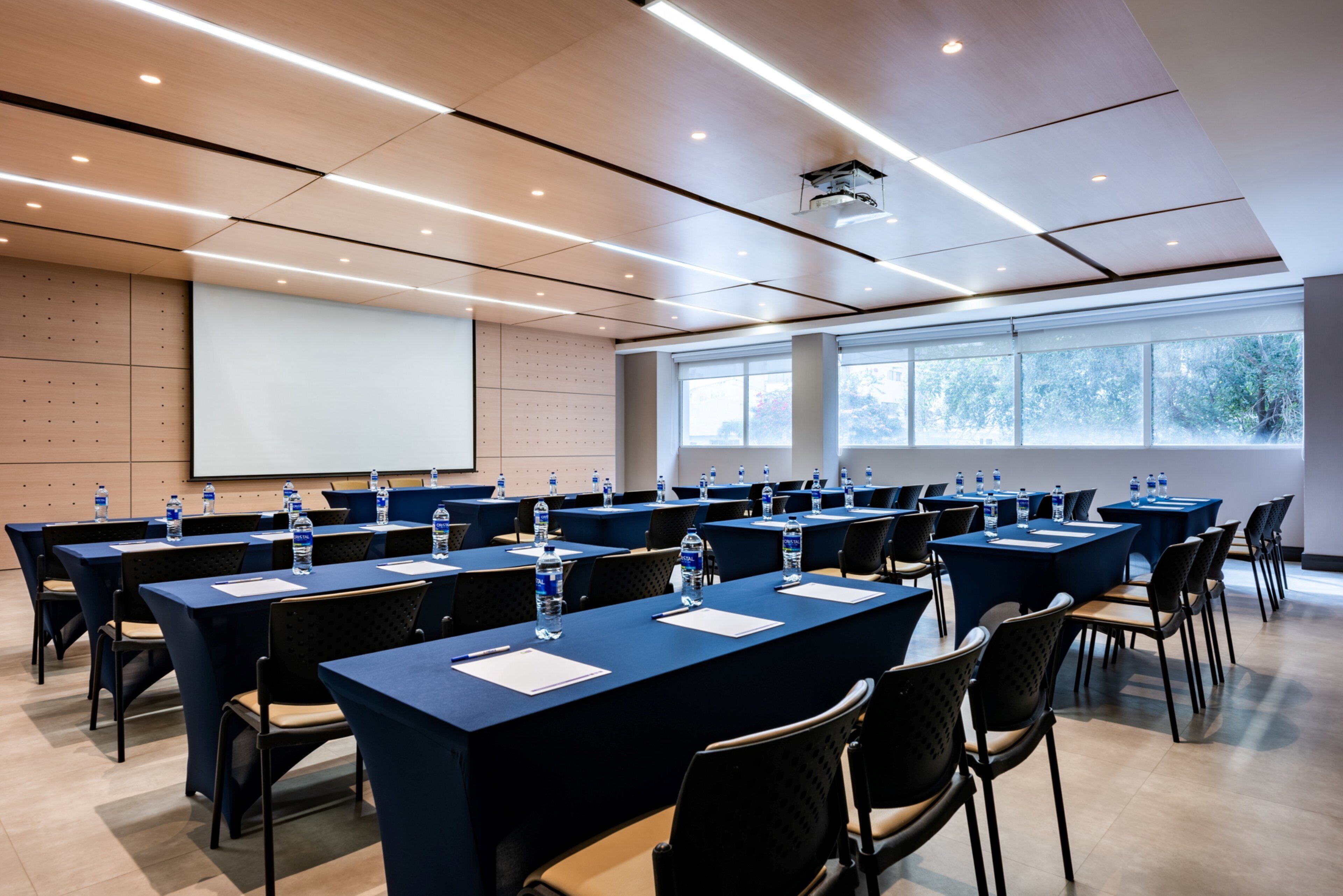 A conference room with multiple tables, chairs, and a projector screen.