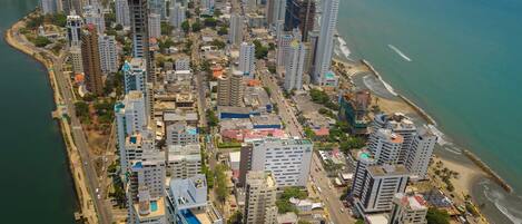 Un paisaje urbano costero con edificios altos, una playa y un puerto deportivo.