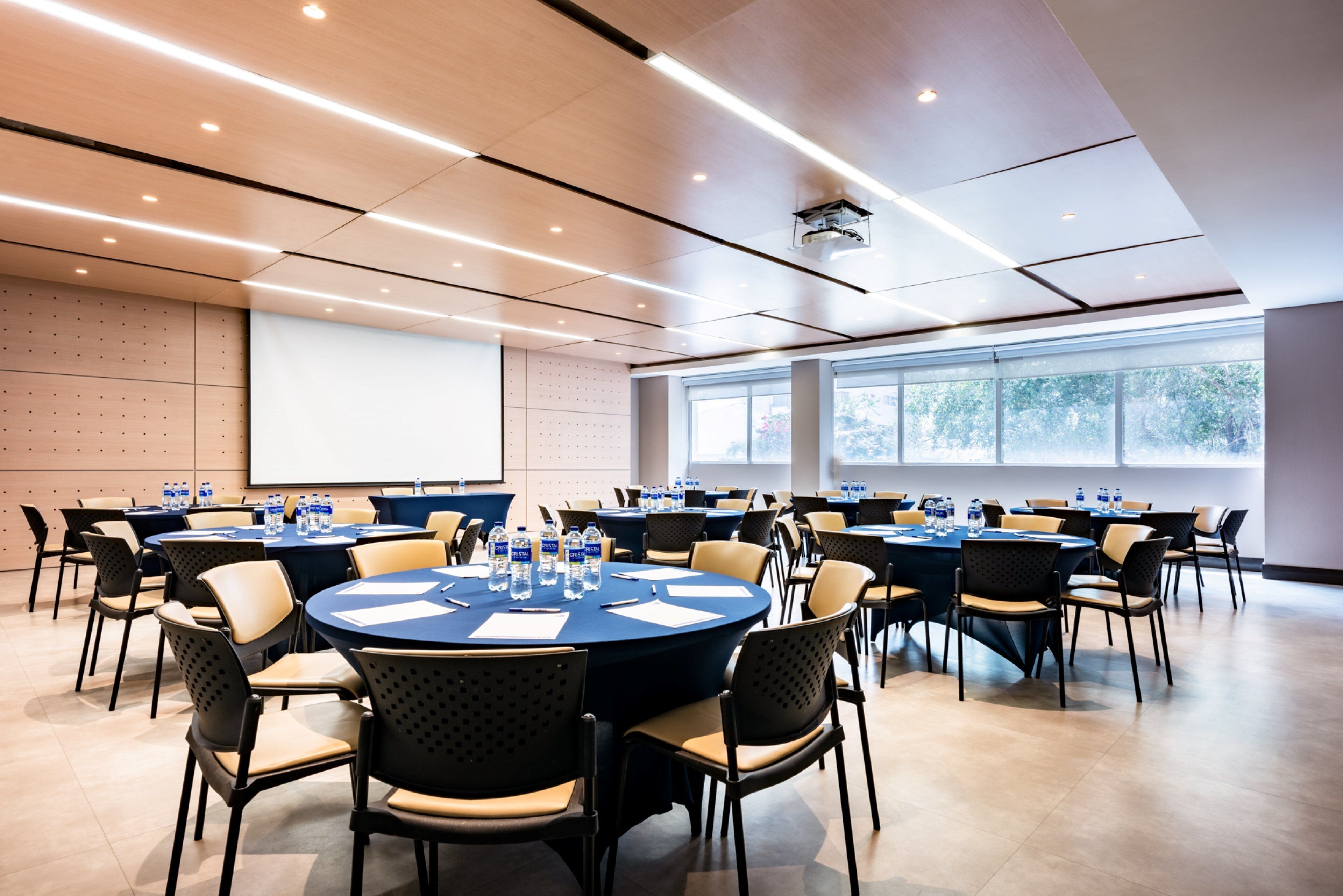 A conference room with multiple round tables, chairs, and water bottles.